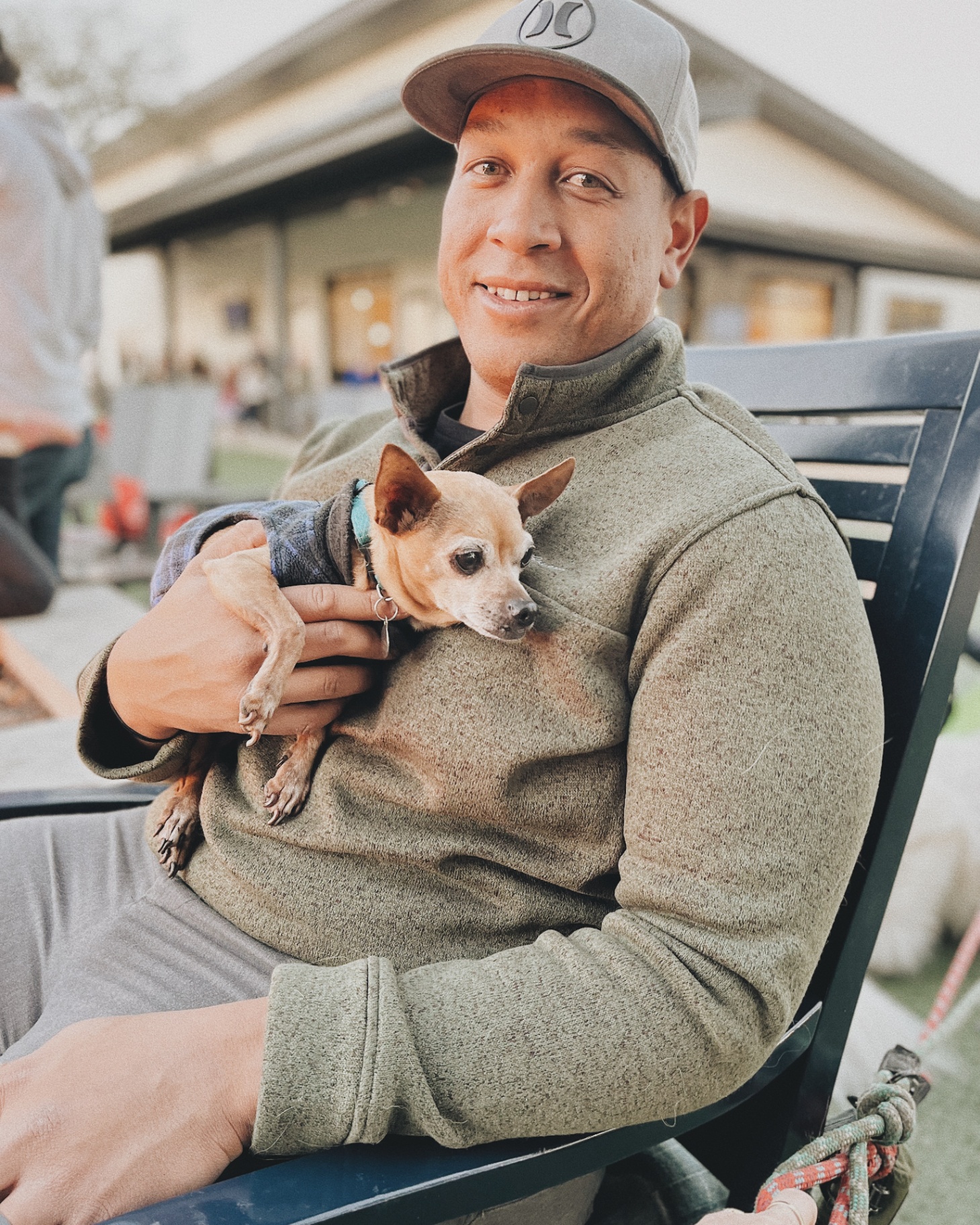 Ben relaxing on a bench holding a senior chihuahua